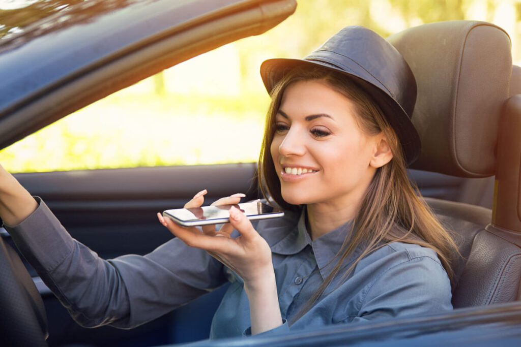 woman in a car holding the phone to do a voice search